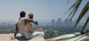 Couple sitting on a ledge overlooking downtown Los Angeles while holding a black Ember Mug.